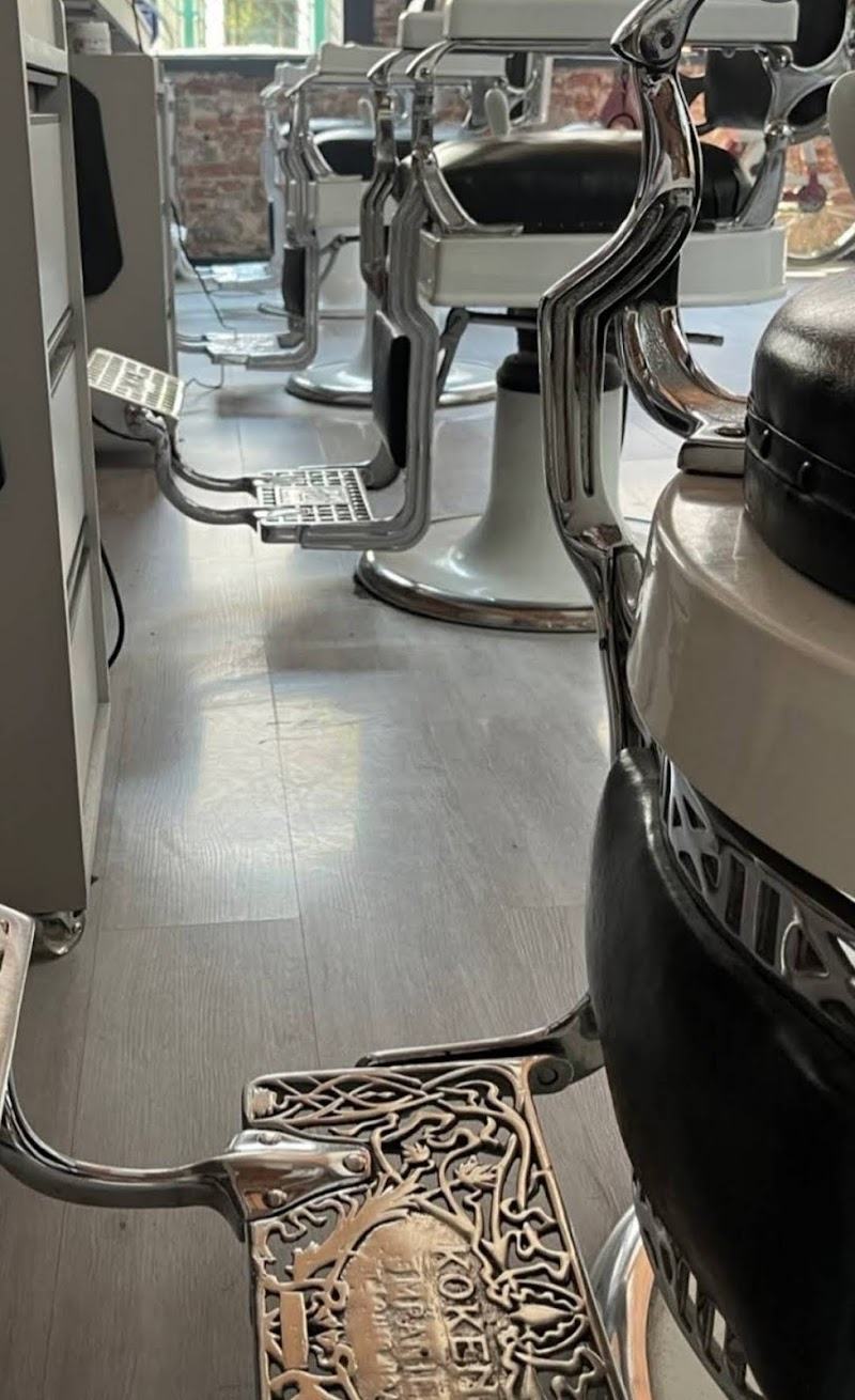 Fila de sillones de barbero cromados con apoyapiés de hierro labrado.