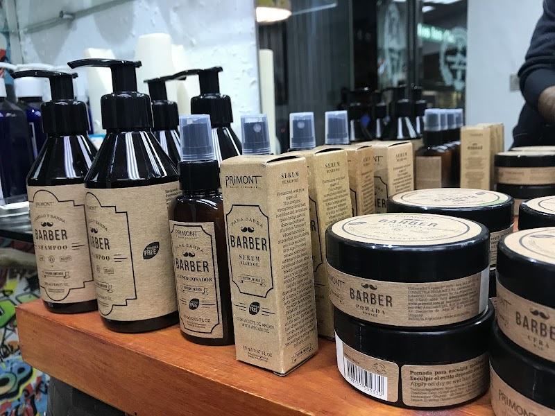 Pomadas, shampoo y aceites de barba alineados sobre la repisa de madera del mostrador.