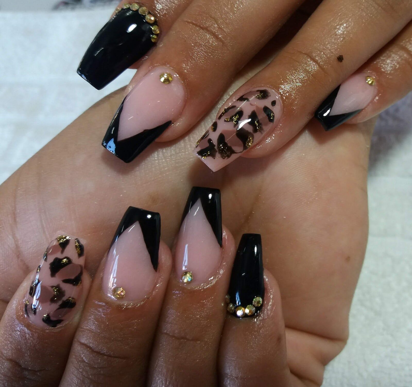 Uñas esculpidas en negro y nude, con pedrería dorada y decoración animal print pintada a mano
