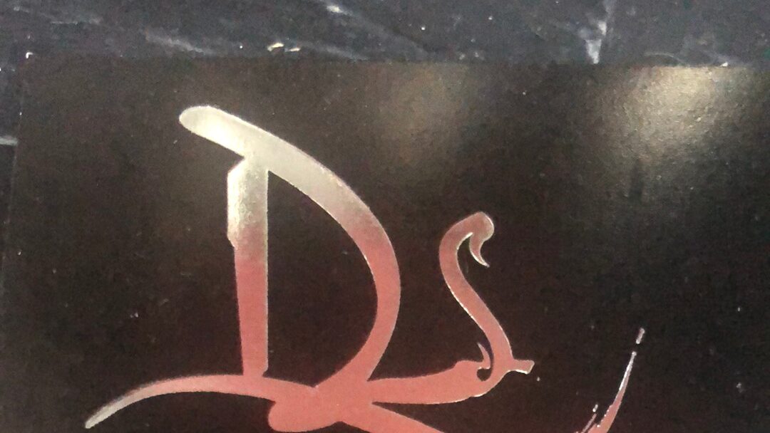 El monograma DS del local, en cobre rosado sobre mármol negro