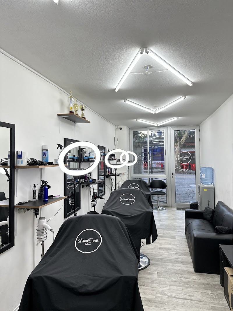 Interior del local: tres sillones, espejos, aros de luz y las capas bordadas con el logo