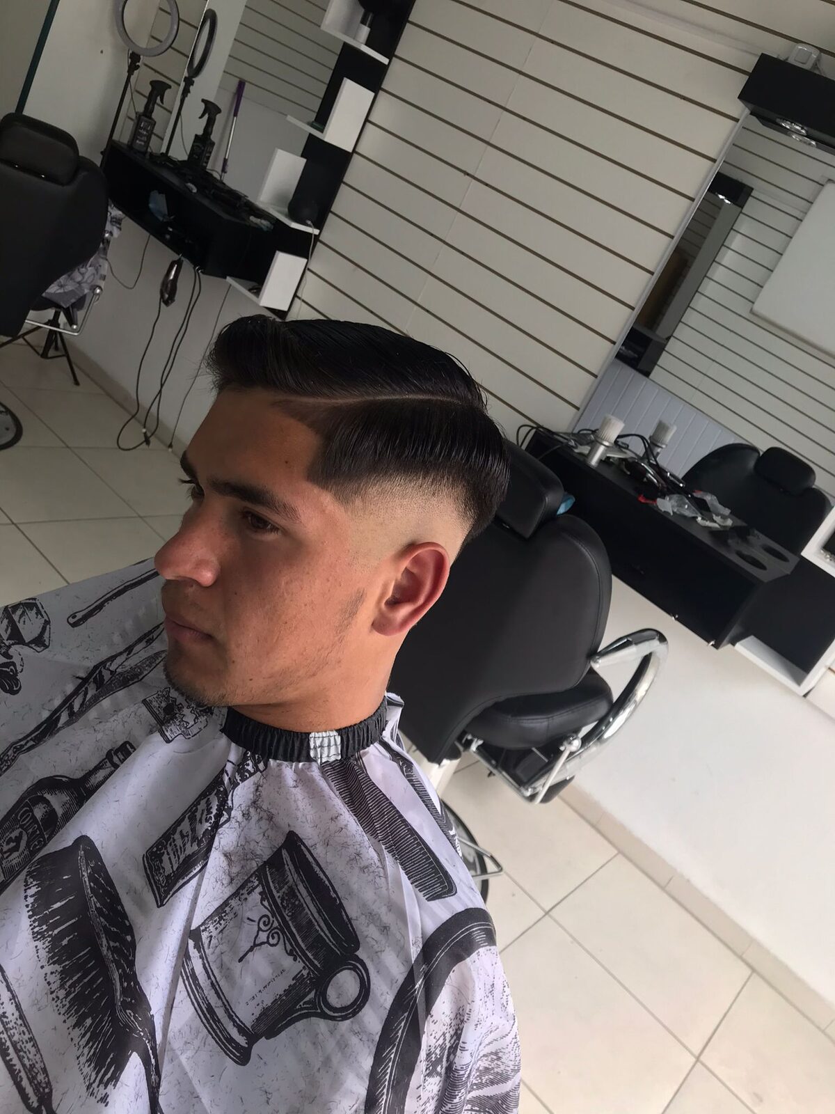 Otro corte terminado, de perfil: degradado en las patillas y volumen peinado hacia atrás.