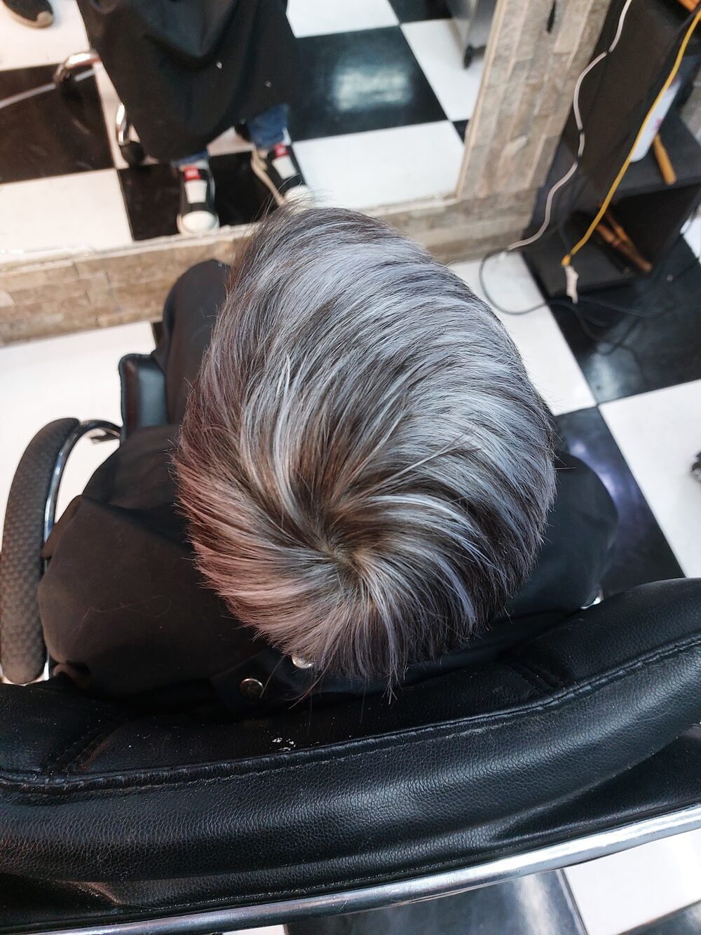Trabajo de color: pelo teñido en gris plata, peinado hacia atrás, sobre el piso de damero