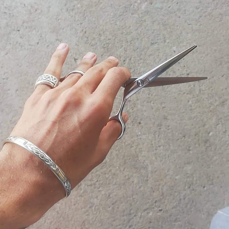 La mano del barbero con la tijera abierta