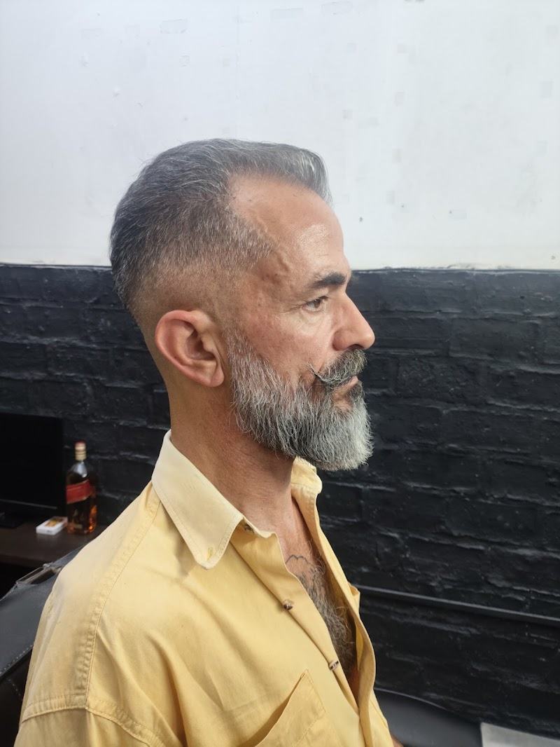 Cliente de perfil con el pelo peinado hacia atrás y la barba prolija
