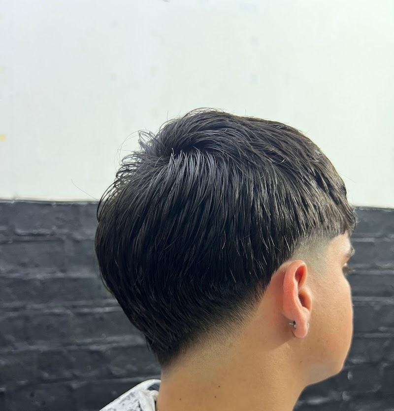 Corte con caída al ras sobre la nuca, contra la pared de ladrillo negro