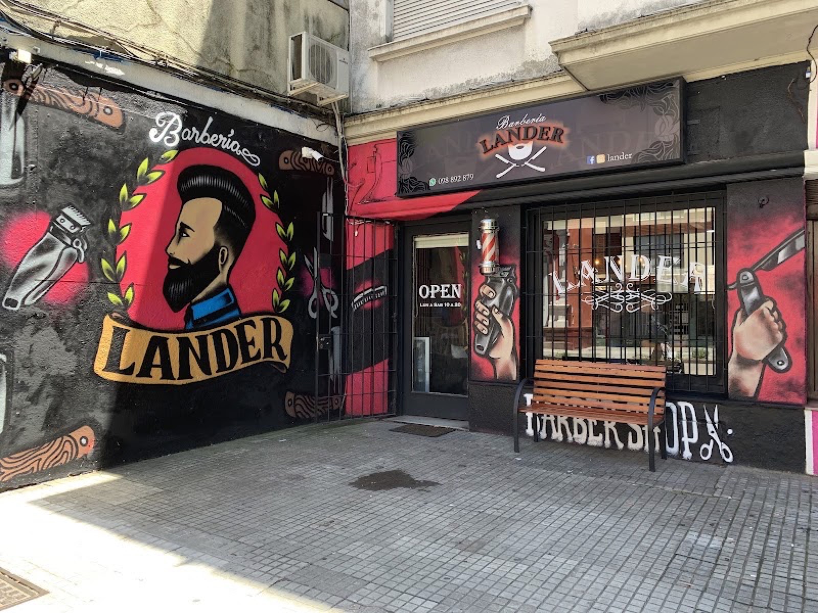 La fachada de Lander en Avenida Rivera, con el mural del barbero y el cartel del local.