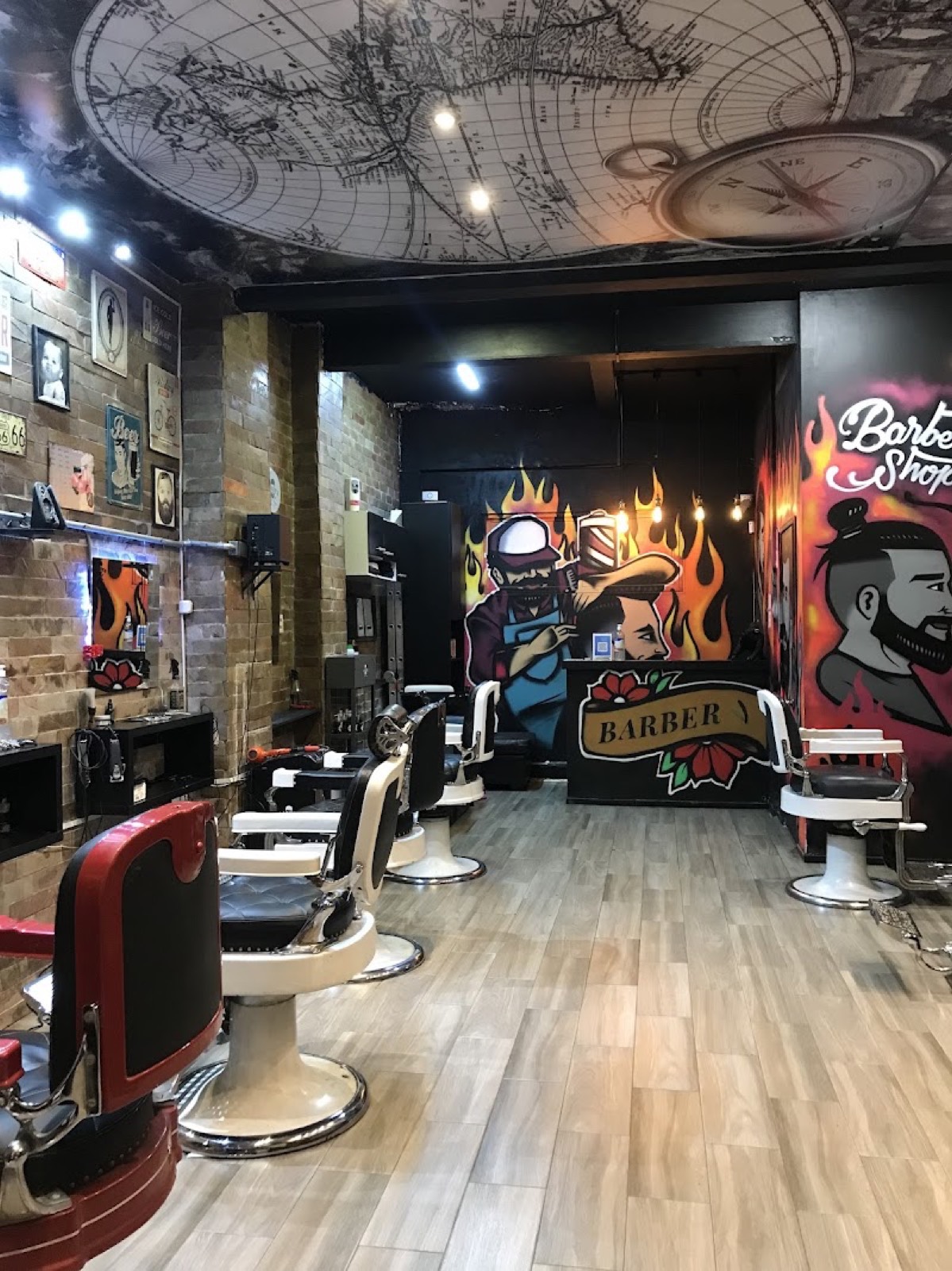 Interior de Lander: los sillones de barbero alineados contra la pared de ladrillo, con murales al fondo.