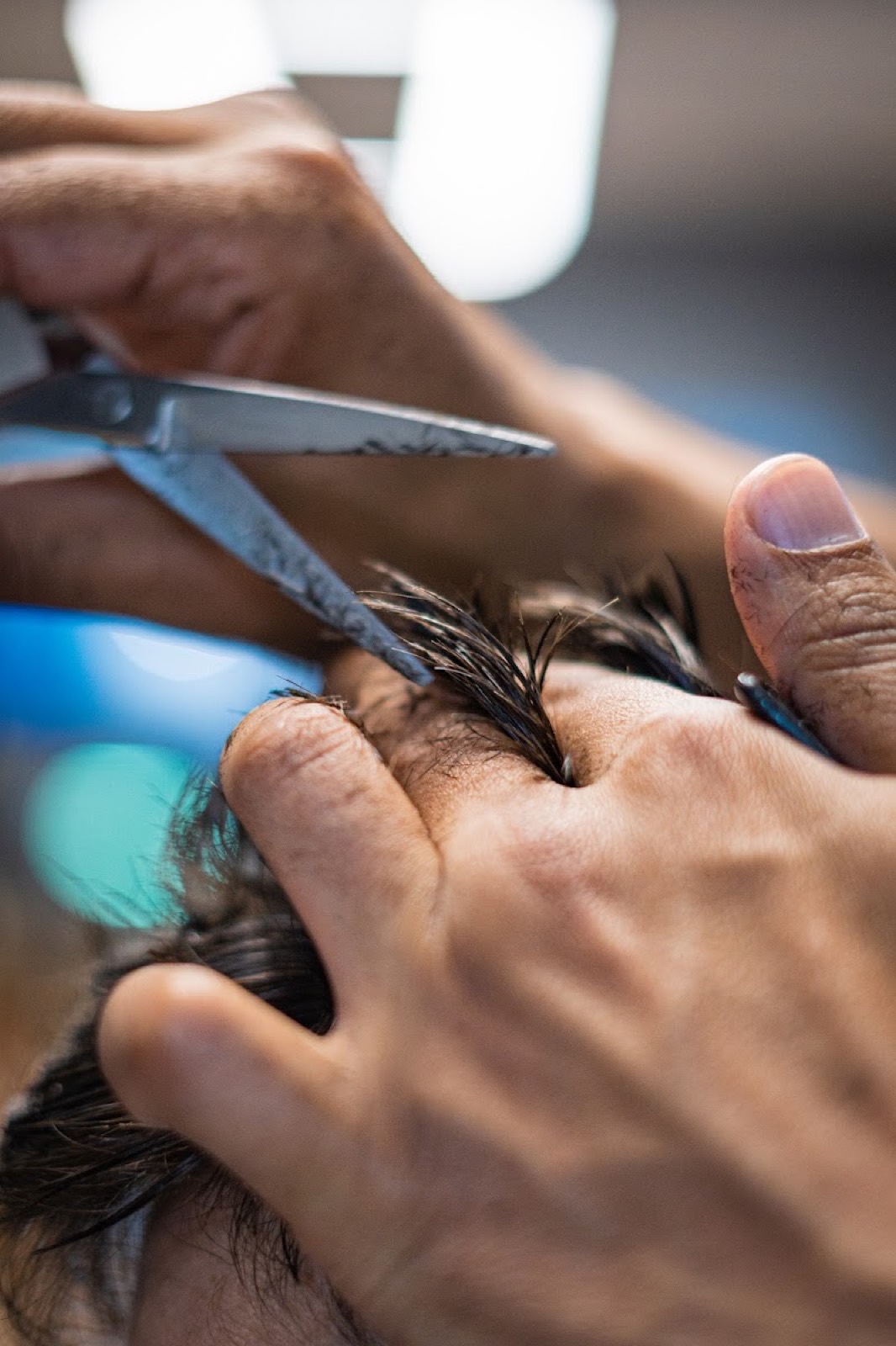 Detalle de tijera cortando el pelo a un cliente.