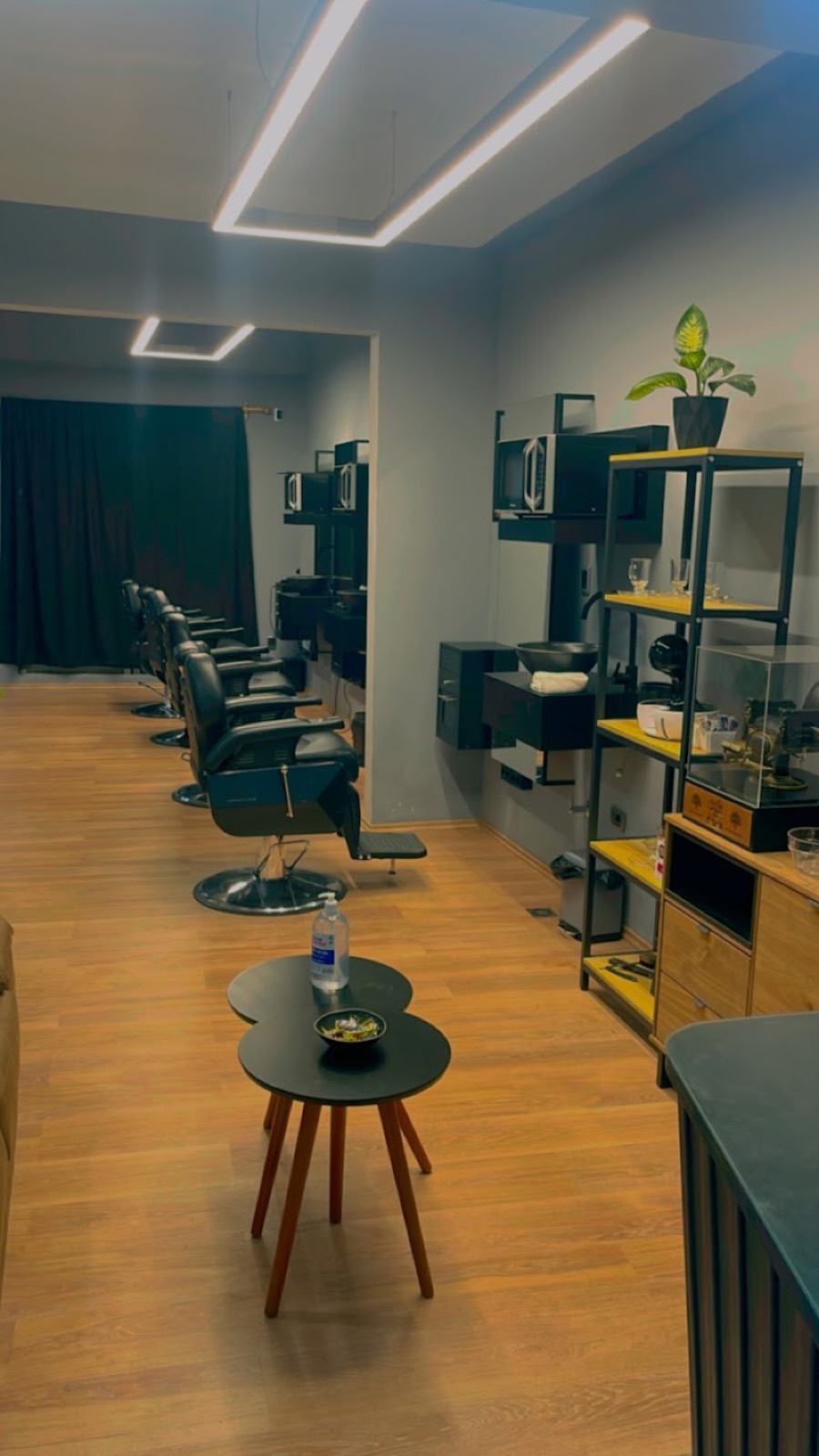 Fila de sillas de barbero vacías con la iluminación del salón encendida.