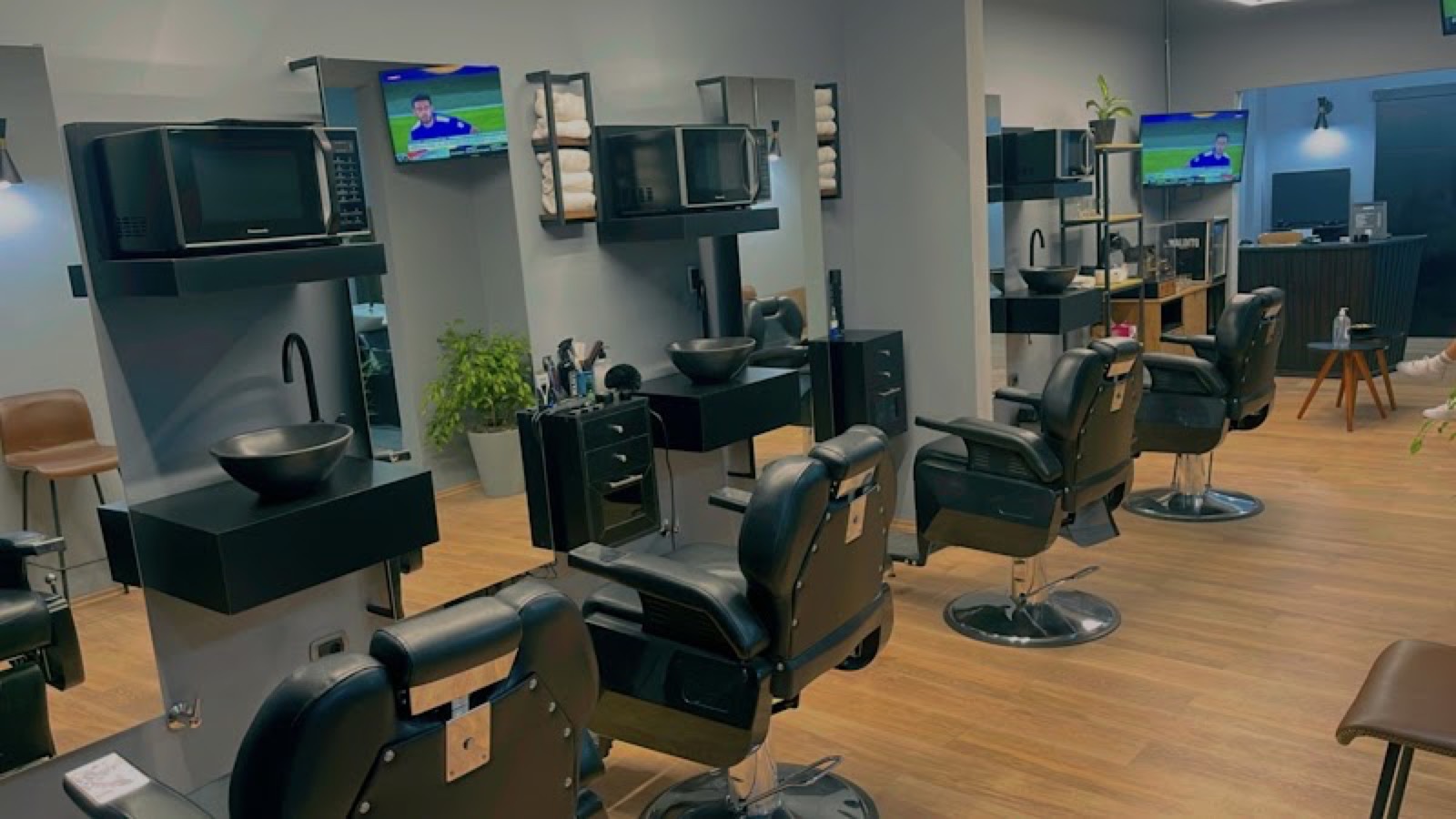 Salón de Maldito Barber Shop: sillas de barbero, espejos y bachas negras sobre piso de madera.