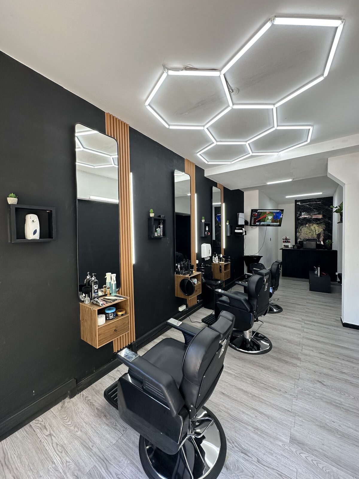 El salón visto de punta: espejos con luz, listones de madera y el techo de tubos LED en panal