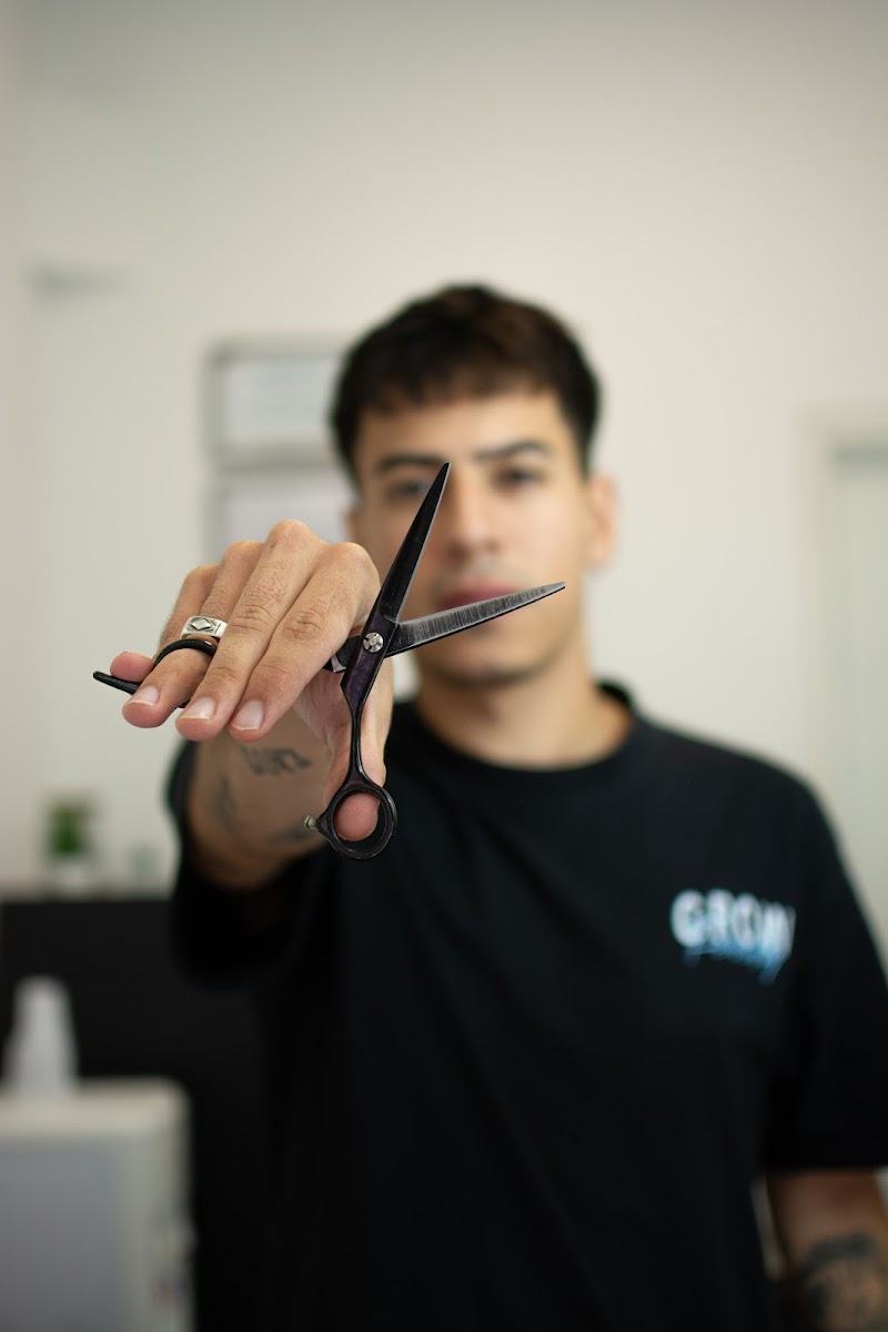 Barbero de Nedo Studio sosteniendo la tijera frente a cámara