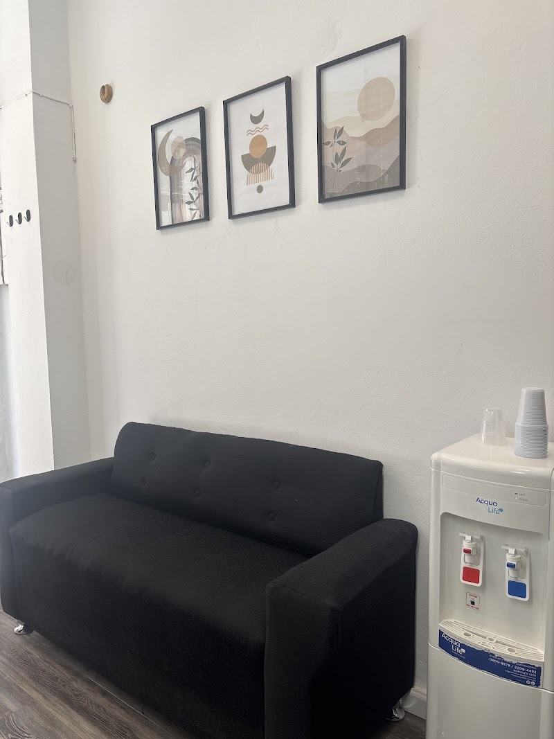 Sala de espera con sofá negro y tres cuadros