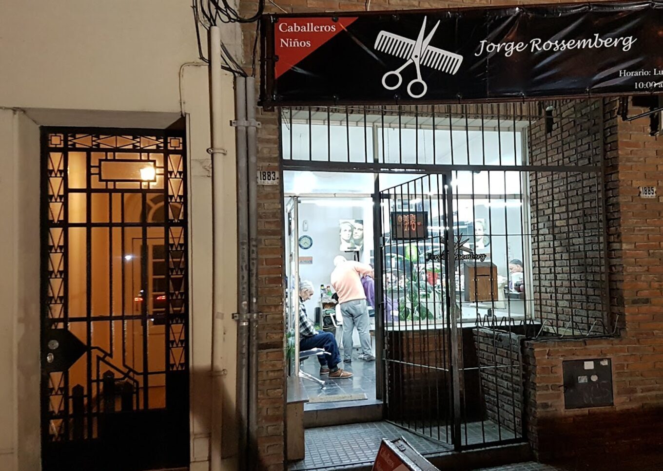 La puerta de la peluquería de noche, con la marquesina negra encendida sobre la vereda de Av. Libertador