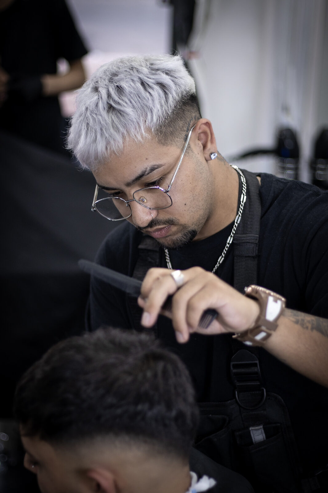 Un barbero de Resbel peinando y cortando con tijera, con la luz fría del salón