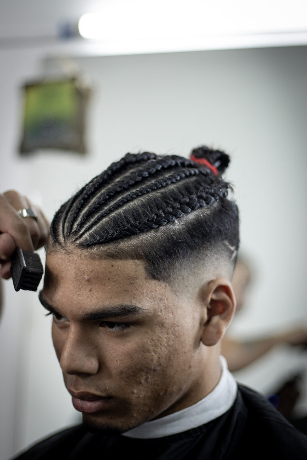 Trenzas cosidas al ras sobre un fade alto, terminadas con brocha