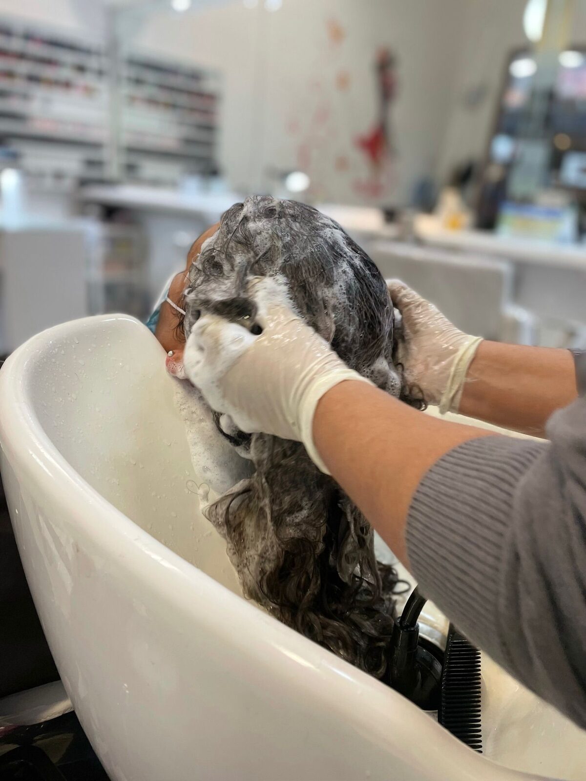 Lavado de cabeza en la bacha del salón, con guantes y espuma