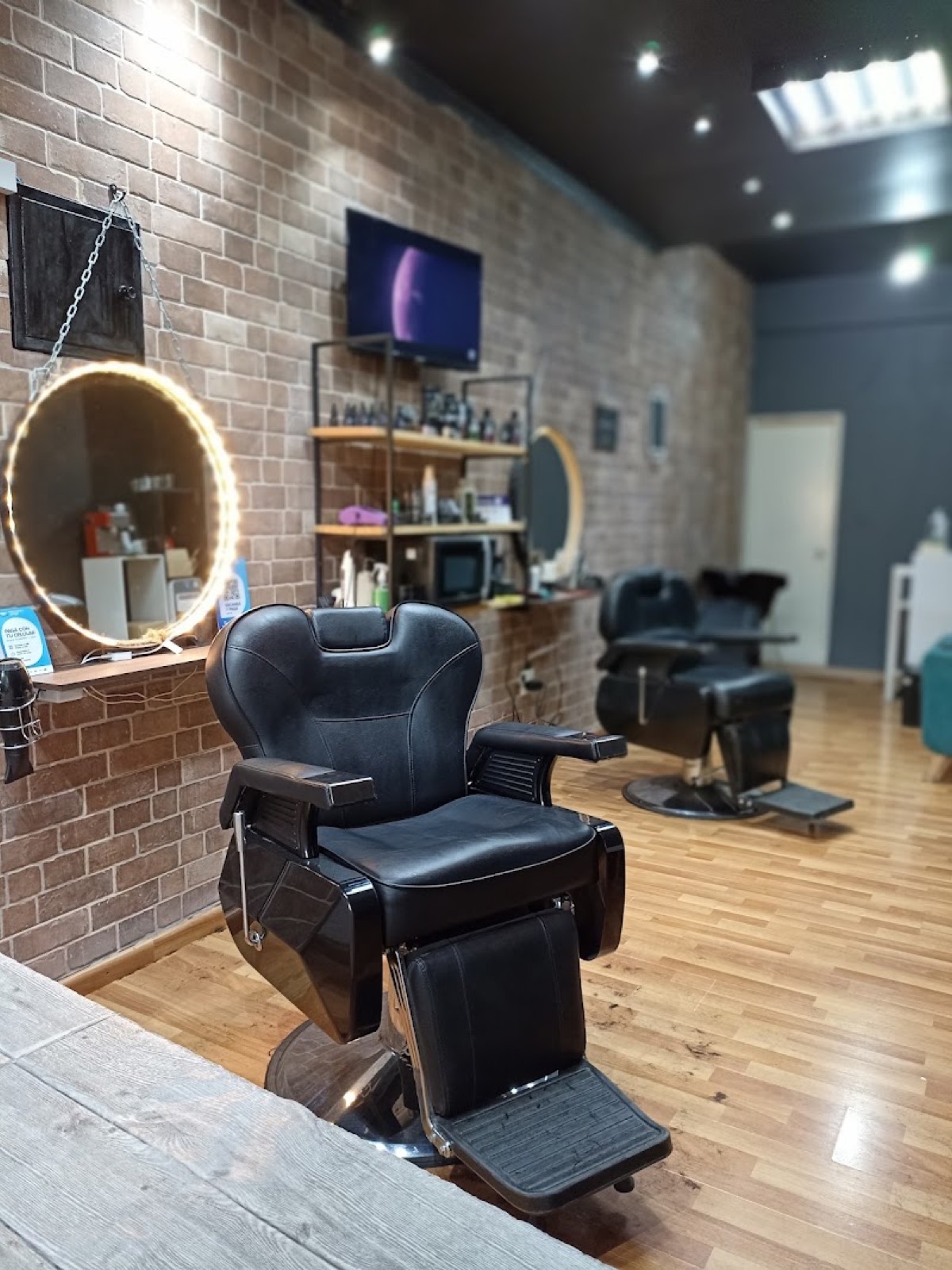 Interior de Studio Zicari: sillón de barbero, pared de ladrillo y espejo con luz