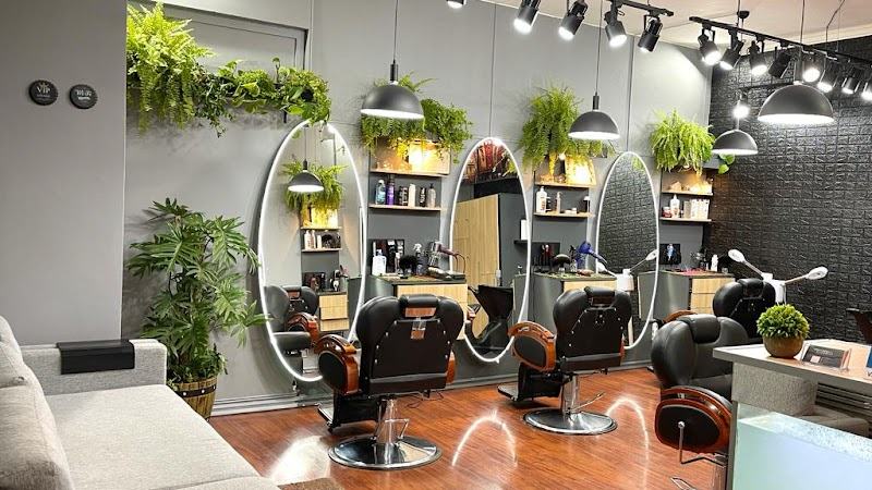 Salón con espejos ovalados iluminados, plantas y los puestos de barbero
