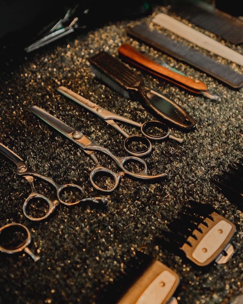 Tijeras de barbero, navaja y peines apoyados sobre pelo recién cortado