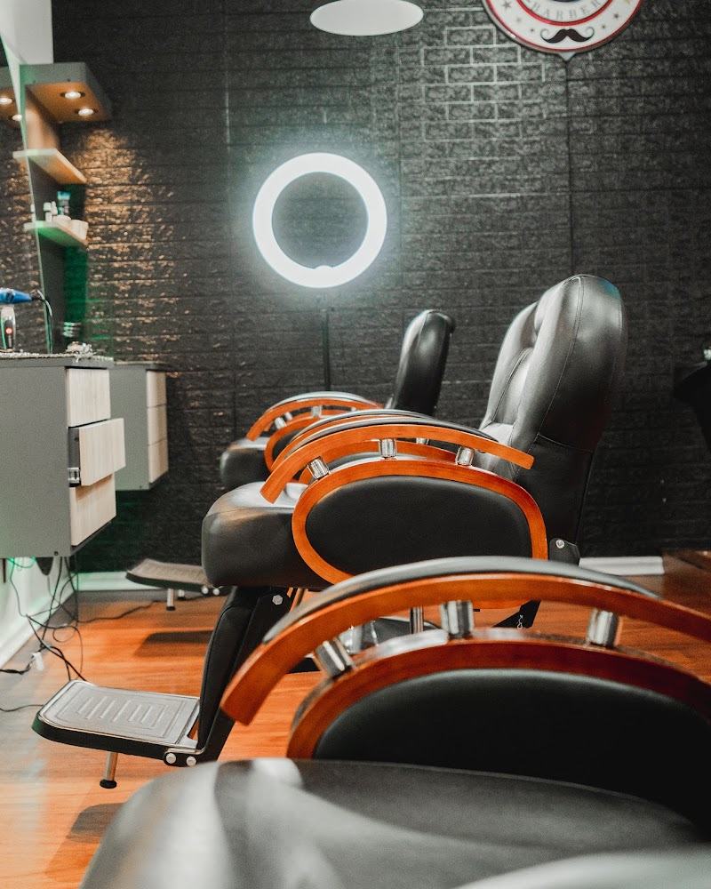 Sillones de barbero de madera y cuero frente a la pared de ladrillo negro
