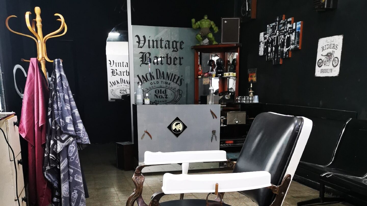 Sillón de barbero antiguo tapizado en cuero, junto al banco de espera